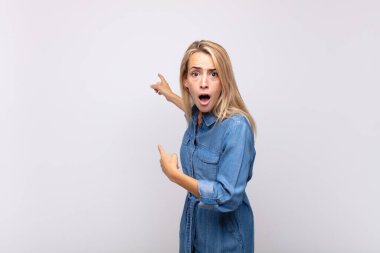 Kadın şaşkın ve şaşırmış hissediyor, yan taraftaki fotokopi alanını işaret ediyor, şaşkın, açık ağızlı bir bakışla.