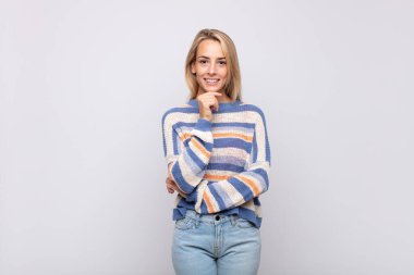 Mutlu görünen ve gülümseyen bir kadın, merak eden ya da soru soran, seçenekleri karşılaştıran.