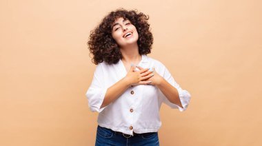 Romantik, mutlu ve aşık bir kadın, neşeyle gülümsüyor ve kalbe yakın el ele tutuşuyor.