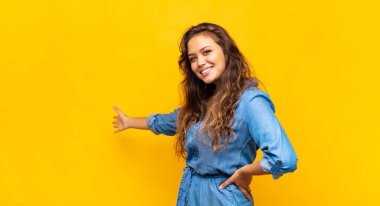 Kız kendini mutlu ve neşeli hissediyor, gülümsüyor ve seni hoş karşılıyor, seni dostça bir jestle içeri davet ediyor.