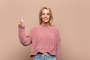 Neşeli ve mutlu bir şekilde gülümseyen bir kadın, tek eliyle boşluğu dolduruyor.