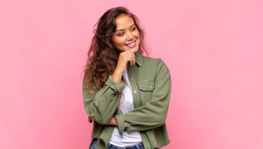 Gülümseyen mutlu, kendine güveni tam bir kız elleri çenesinde, merakla yan tarafa bakıyor.