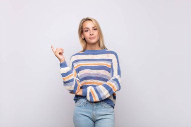 Kadın mutlu bir şekilde gülümsüyor ve yan bakıyor, merak ediyor, düşünüyor ya da bir fikri var.