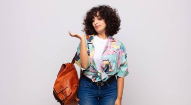 Kadın kendini mutlu hissediyor ve gelişigüzel gülümsüyor. Elinde tuttuğu bir nesneye ya da konsepte bakıyor.