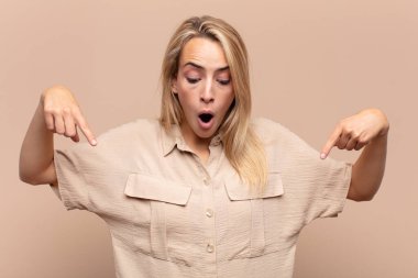 Kadın şok olmuş, ağzı açık ve şaşkın, inançsızlık ve şaşkınlık içinde bakıyor ve onu işaret ediyor.