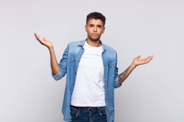  Şaşırmış, kafası karışmış ve stresli görünüyor, farklı seçenekler arasında merak ediyor, kararsız hissediyor.