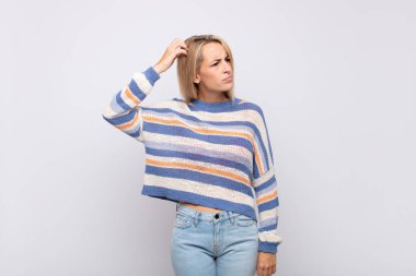 Kadın şaşkın ve şaşkın hissediyor, başını kaşıyor ve yan tarafa bakıyor.