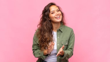 Kadın kendini mutlu ve başarılı hissediyor, gülümsüyor ve alkışlıyor, alkışlarla tebrik ediyor.