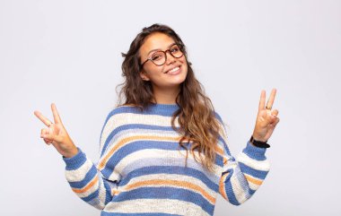 Gülümseyen ve mutlu görünen bir kadın, dost canlısı ve tatmin olmuş, zafer ya da barış simgesi
