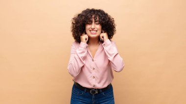 Kızgın, stresli ve sinirli görünen bir kadın, iki kulağını da sağır edici bir sese, sese ya da gürültüye kapatıyor.