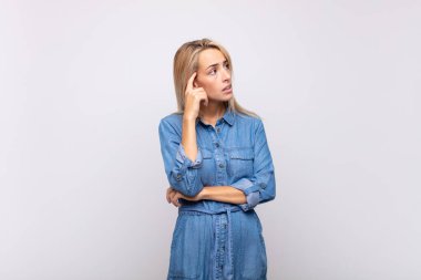 Yoğunlaşmış bakışlı, şüpheli bir ifadeyle, yukarı ve yana bakan bir kadın.