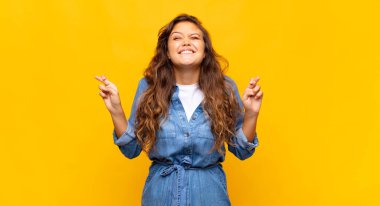 Kadın gülümsüyor ve endişeyle parmaklarını çaprazlıyor, endişeli ve iyi şanslar diliyor.