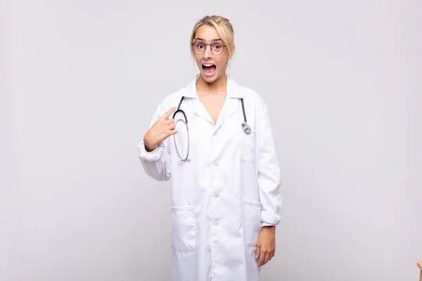 Mladá Žena Lékař Vypadá Šokován Překvapen Ústy Dokořán Ukazuje Sebe — Stock fotografie