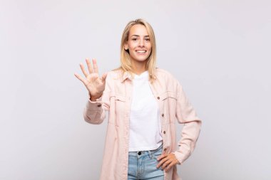 Gülümseyen ve arkadaş canlısı görünen bir kadın, 5 ya da 5 numarayı gösteriyor, eli önde, geri sayıyor.