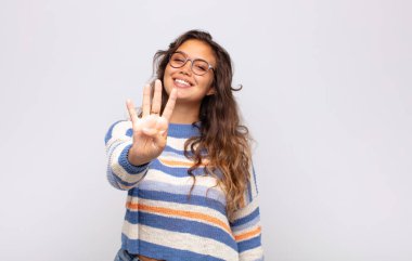 Kadın gülümsüyor ve arkadaş canlısı görünüyor, 4 ya da 4 numarayı gösteriyor, eli önde, geri sayıyor.