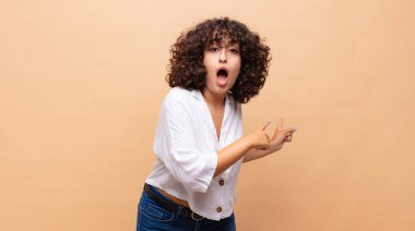 Kadın şaşkın ve şaşırmış hissediyor, yan taraftaki fotokopi alanını işaret ediyor, şaşkın, açık ağızlı bir bakışla.