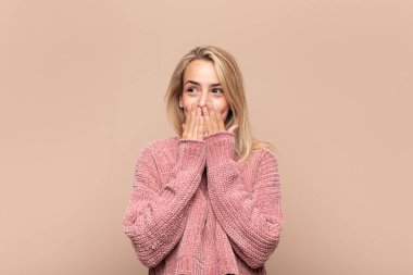 Kadın mutlu ve heyecanlı, şaşırmış ve şaşırmış elleriyle ağzını kapatmış, tatlı bir ifadeyle kıkırdıyor.