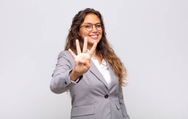 Kadın gülümsüyor ve arkadaş canlısı görünüyor, 4 ya da 4 numarayı gösteriyor, eli önde, geri sayıyor.