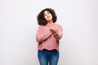 Bir kadın mutlu ve aşık, bir eli kalbinin yanında, diğer eli önde uzanmış gülümsüyor.