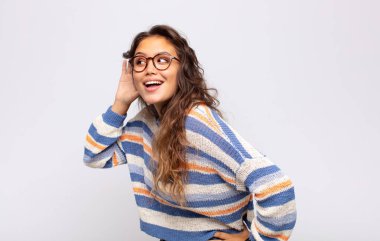 Gülümseyen bir kadın, tuhaf bir şekilde yan tarafa bakıyor, dedikoduları dinlemeye ya da bir sırrı duymaya çalışıyor.