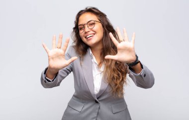 Gülümseyen ve arkadaş canlısı görünen bir kadın, onuncu veya onuncu numarayı gösteriyor, eli önde, geri sayıyor.