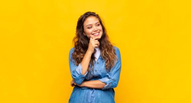 Gülümseyen mutlu, kendine güveni tam bir kadın elleri çenesinde, merak ediyor ve yan tarafa bakıyor.