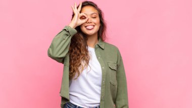 Komik yüzüyle mutlu bir şekilde gülümseyen, şakalaşan ve gözetleme deliğinden bakan, sırları gözetleyen bir kadın.