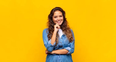 Mutlu görünen ve gülümseyen bir kadın, merak eden ya da soru soran, seçenekleri karşılaştıran.