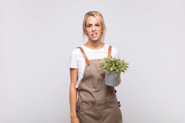 young woman gardener feeling puzzled and confused, with a dumb, stunned expression looking at something unexpected