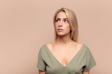 Endişeli, kafası karışık, budala bir kadın, kopya alanına bakıyor, şüphe ediyor.