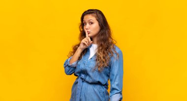 Kadın sessizlik ve sessizlik istiyor, parmaklarıyla ağzının önünde işaret ediyor, 