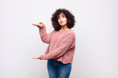 Bir objeyi iki elinde tutan kadın fotokopi alanında, bir nesneyi gösterir, sunar ya da reklamını yapar.