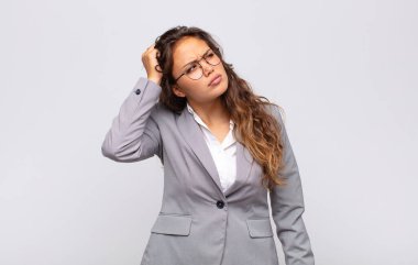 Kadın şaşkın ve şaşkın hissediyor, başını kaşıyor ve yan tarafa bakıyor.