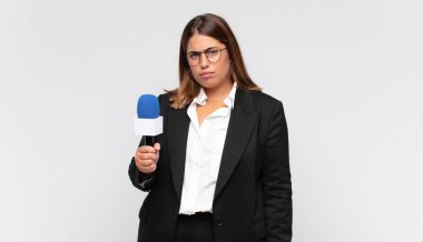 Genç kadın muhabir üzgün, üzgün ya da kızgın hissediyor ve olumsuz bir tavır takınıyor, anlaşmazlık içinde kaşlarını çatıyor.