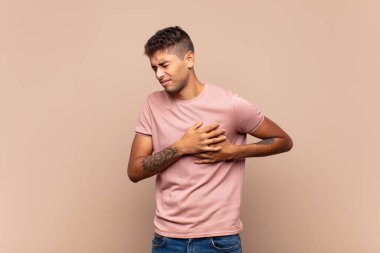  Üzgün, yaralı ve kalbi kırık görünüyor, iki elini de kalbe yakın tutuyor, ağlıyor ve depresif hissediyor.