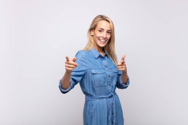 Pozitif, başarılı, mutlu bir tavırla gülümseyen kadın kamerayı işaret ederek, elleriyle silah işareti yapıyor.