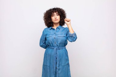 Kadın ciddi, güçlü ve asi hissediyor, yumruğunu kaldırıyor, protesto ediyor ya da devrim için savaşıyor.