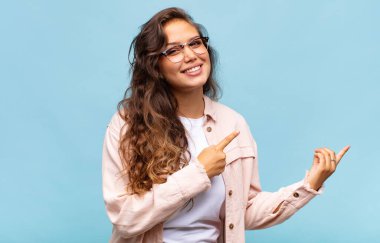 Mutlu bir şekilde gülümseyen ve iki elini de fotokopi uzayında gösteren bir kadın.