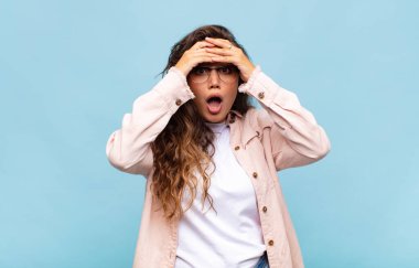 Kadın dehşete kapılmış ve şok olmuş hissediyor, ellerini havaya kaldırıyor ve hata yaptığında panikliyor.