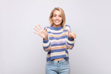 Gülümseyen ve arkadaş canlısı görünen bir kadın, 6 ya da 6 numarayı gösteriyor, elleri önde, geri sayıyor.