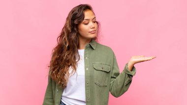 Kadın kendini mutlu hissediyor ve gelişigüzel gülümsüyor. Elinde tuttuğu bir nesneye ya da konsepte bakıyor.