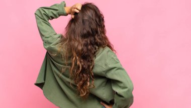 Kadın kendini cahil ve kafası karışık hissediyor, bir çözüm düşünüyor, eli kalçasında, diğeri kafasında, dikiz aynasından.