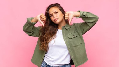 Üzgün, hayal kırıklığına uğramış ya da kızgın görünen bir kadın. Anlaşmazlıkta baş parmağını gösteriyor. Hayal kırıklığına uğramış hissediyor.