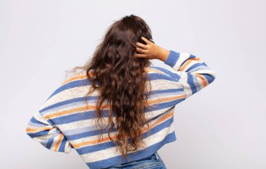 Kadın kendini cahil ve kafası karışık hissediyor, bir çözüm düşünüyor, eli kalçasında, diğeri kafasında, dikiz aynasından.