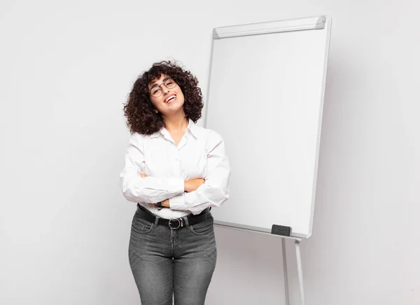 Woman looking like a happy, proud and satisfied achiever smiling with arms crossed