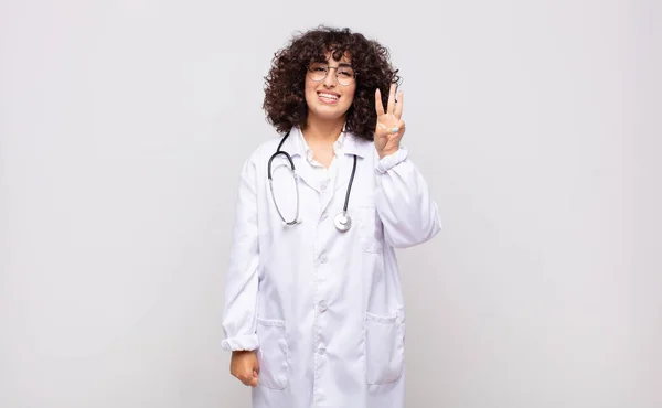 Ung Kvinna Läkare Ler Och Ser Vänlig Visar Nummer Tre — Stockfoto