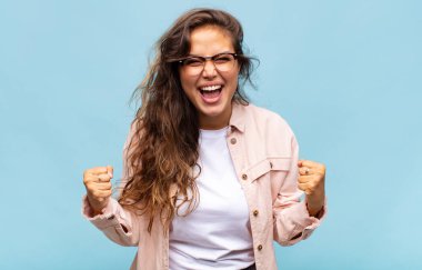 Kadın mutlu, şaşırmış ve gururlu, bağırıyor ve başarıyı büyük bir gülümsemeyle kutluyor.