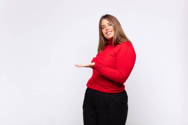 Genç sarışın kadın neşeyle gülümsüyor, mutlu hissediyor ve fotokopi uzayda bir konsept gösteriyor.