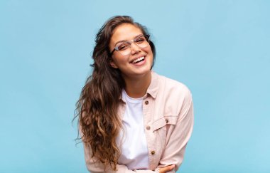 Kadın utangaç ve neşeli bir şekilde gülüyor, arkadaş canlısı ve olumlu ama güvensiz bir tavırla.