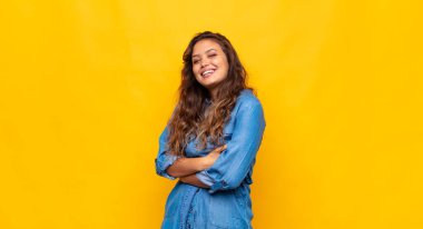 Kadın kollarını kavuşturup mutlu bir şekilde gülüyor, rahat, pozitif ve tatmin olmuş bir şekilde.